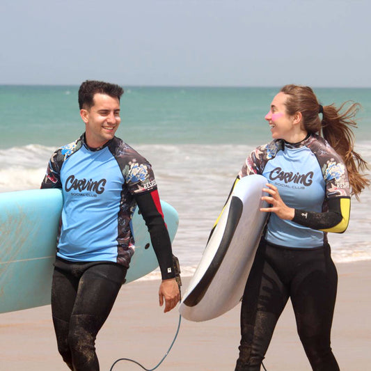 Pareja caminando por la playa con tablas de surf en El Palmar