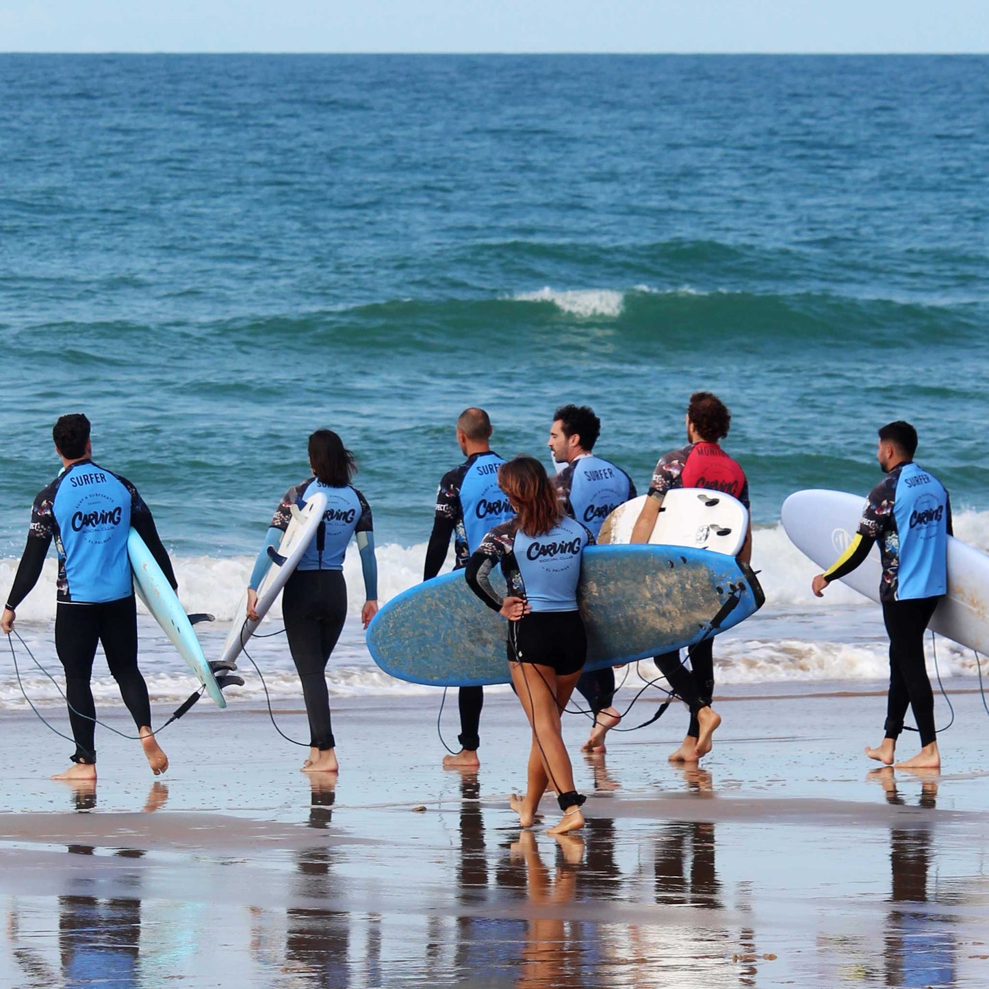 Alumnos de Carving Social Club entrando al agua durante un surfcamp festivo