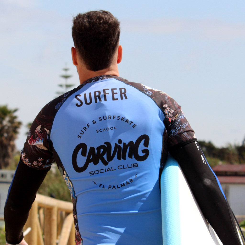Surfista con tabla y licra de Carving Social Club en El Palmar
