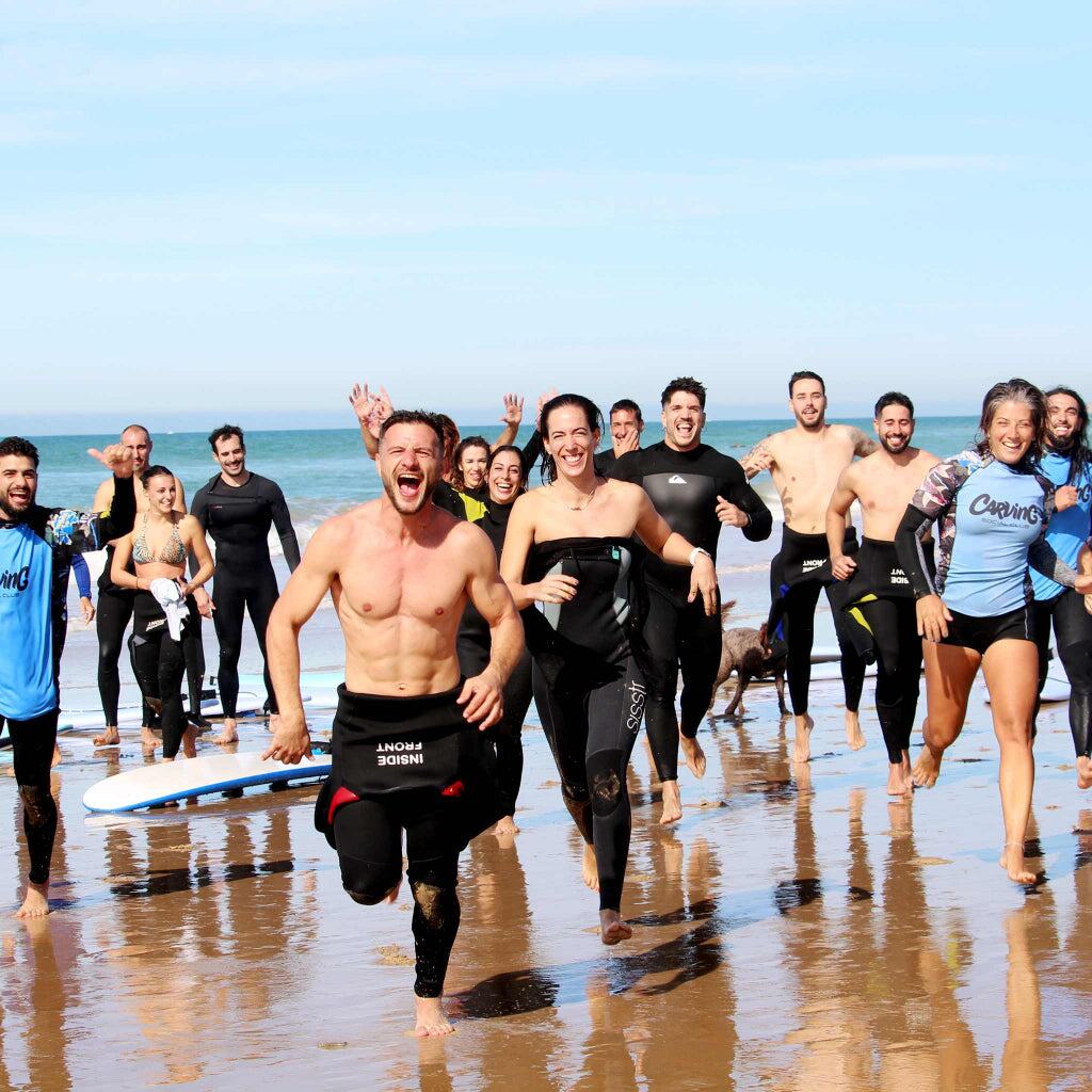 Grupo de adultos disfrutando de la experiencia de surfcamp en la playa de El Palmar, Cádiz.
